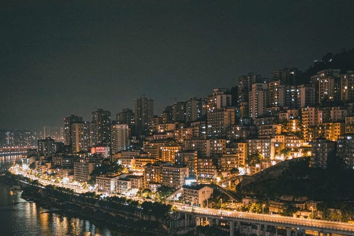 Luzes de Chongqing refletidas no rio, com prédios em vários níveis