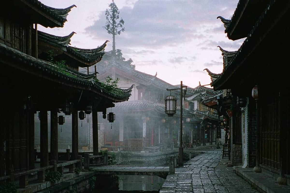 Rua de pedra da cidade antiga de Lijiang com canal e lanternas