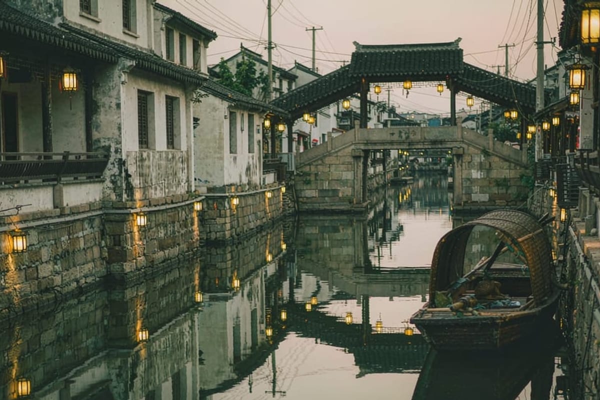 Canal de Suzhou ao anoitecer com barco e lanternas