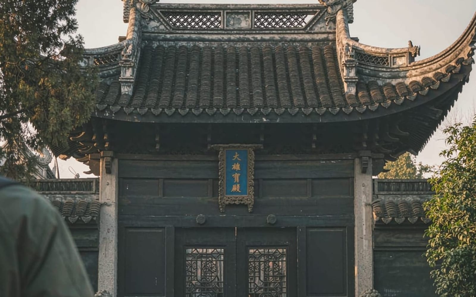 Guia em português com um grupo pequeno na entrada de um templo chinês