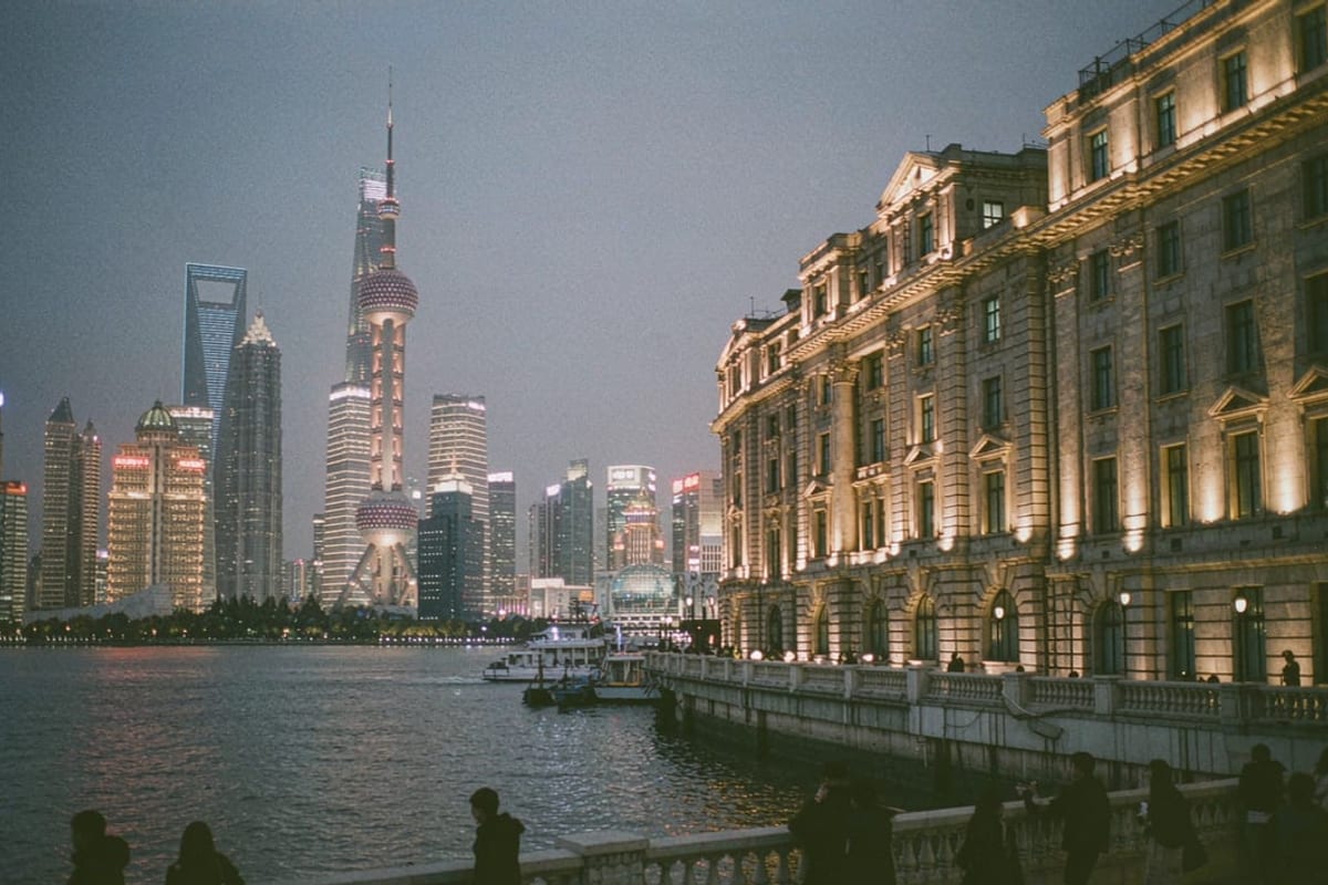 Fachadas iluminadas do Bund à noite, com o skyline de Pudong do outro lado do rio