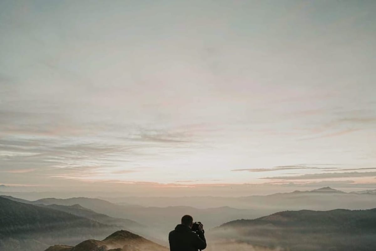 Fotógrafo com tripé em mirante ao amanhecer