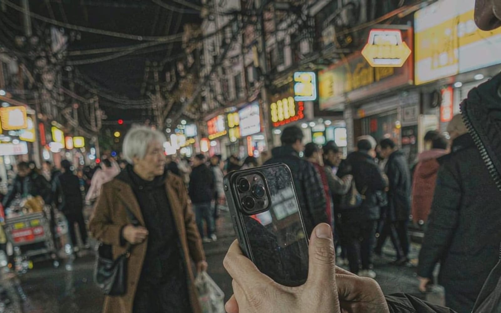 Pessoa com celular em rua chinesa à noite
